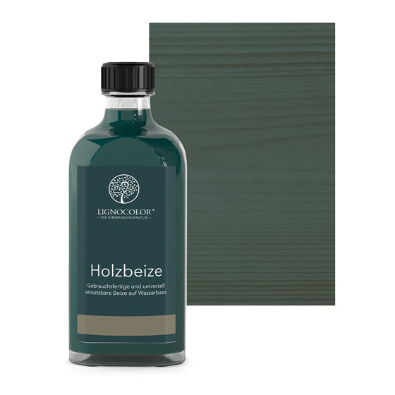 Holzbeize Blaugrün in der Glasflasche mit gebeiztem Holz im Hintergrund.