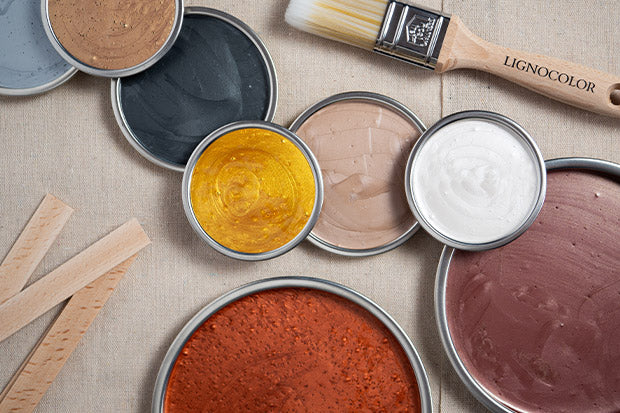 Mehrere Farbtöne der Metallicfarbe für Wände auf einem Tisch präsentiert