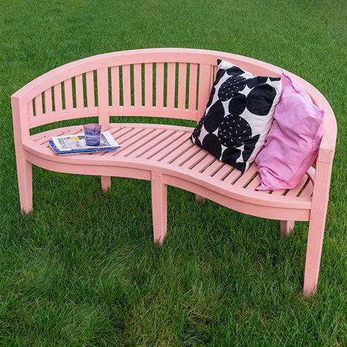 Pink gestrichene Gartenbank auf einer Wiese