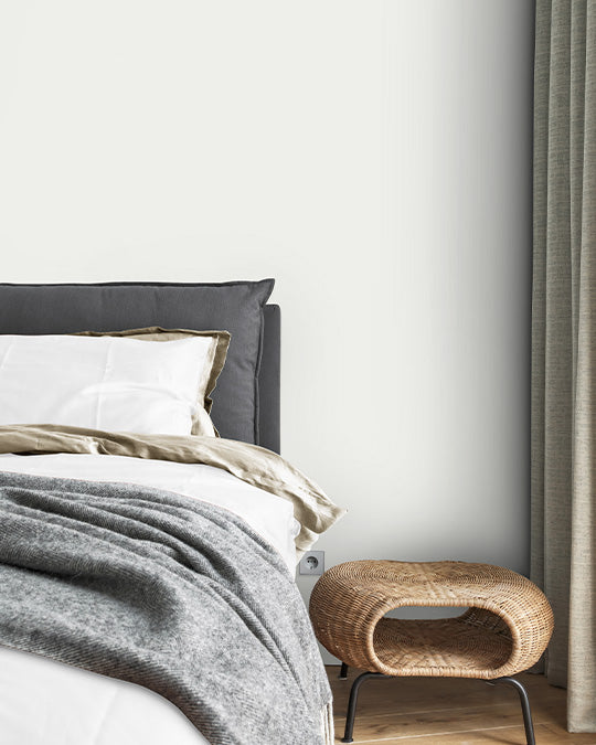 Weiße Schlafzimmerwand hinter Bett und Nachtschrank