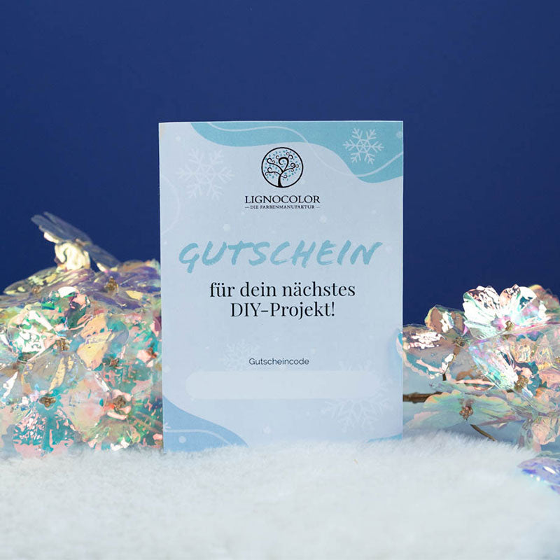 Weihnachtliche Gutscheinkarte in Schnee steckend vor blauer Wand