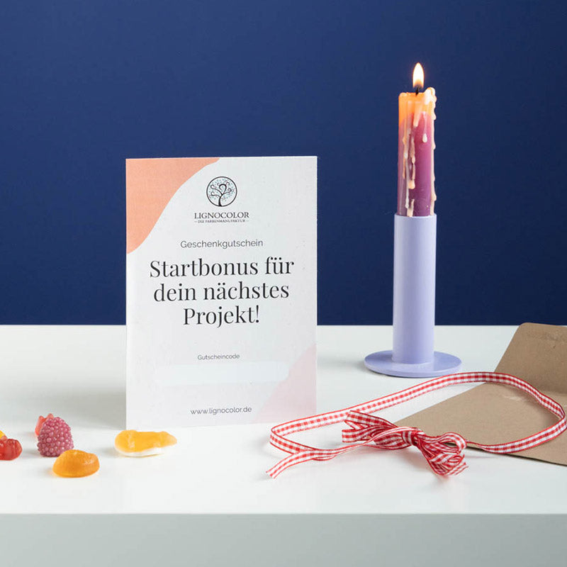 Gutscheinkarte auf einem weißen Tisch mit einer Kerze vor blauer Wand