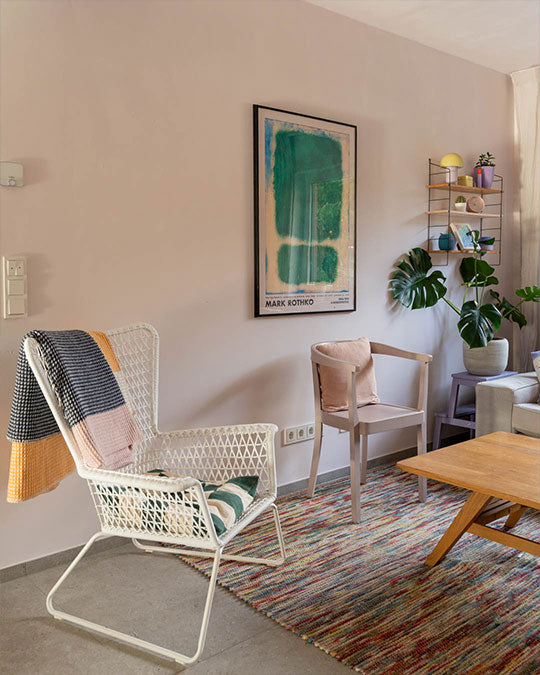 Schaukelstuhl im Wohnzimmer vor einer Wand in einem zarten und pastelligen Rosa-Farbton.