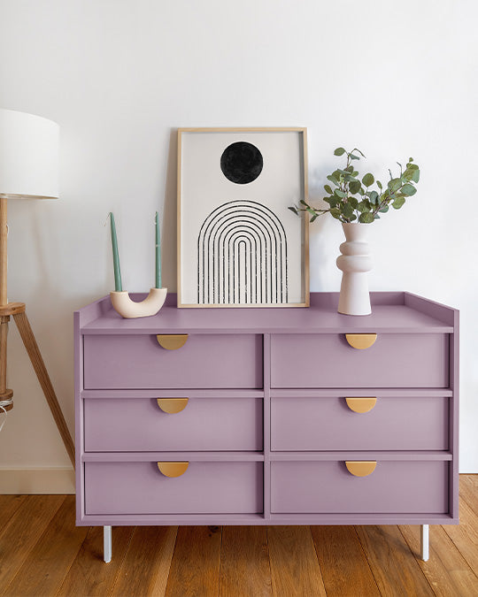 Lila Kommode vor weißer Wand im Wohnzimmer