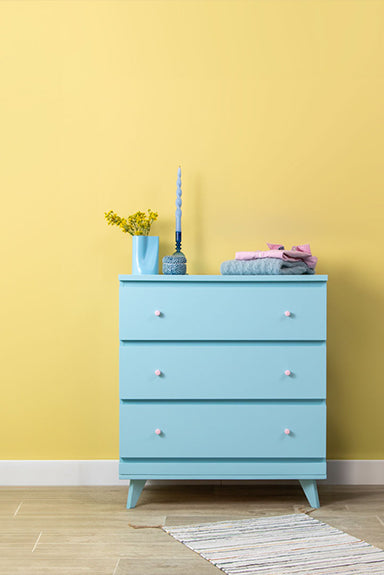 Blaue Kommode vor gelber Wand mit Wandfarbe Sierra Nevada von Lignocolor